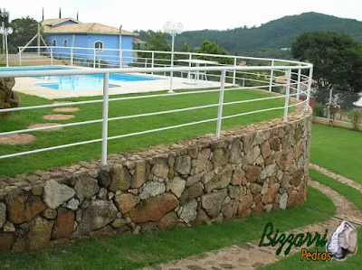 Construção da piscina em residência com os muros de pedra ornamental com os caminhos de pedra.