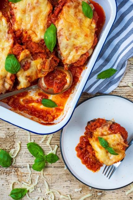 This Eggplant Parmesan is a classic comforting Italian dish makes great use of the wonderful purple vegetable. Gooey cheese on top of a delicious homemade tomato sauce with eggplant (aubergine) halves as the base. A great dish to boost your veggie intake, and fancy enough to wow guests too. No breading, no frying, just healthy comfort food!