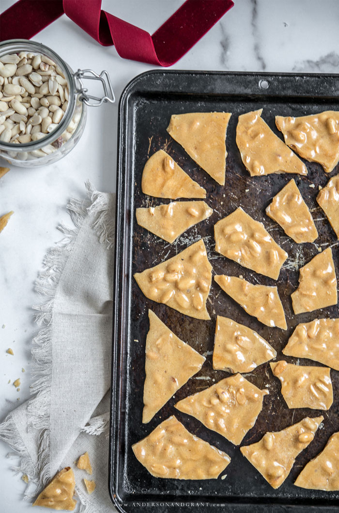 Make homemade peanut brittle to enjoy this Christmas and to share with friends and family. Baking sheet filled with pieces of peanut brittle.