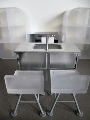 Modern dolls' house miniature white and grey kitchen set up, with concrete floor.