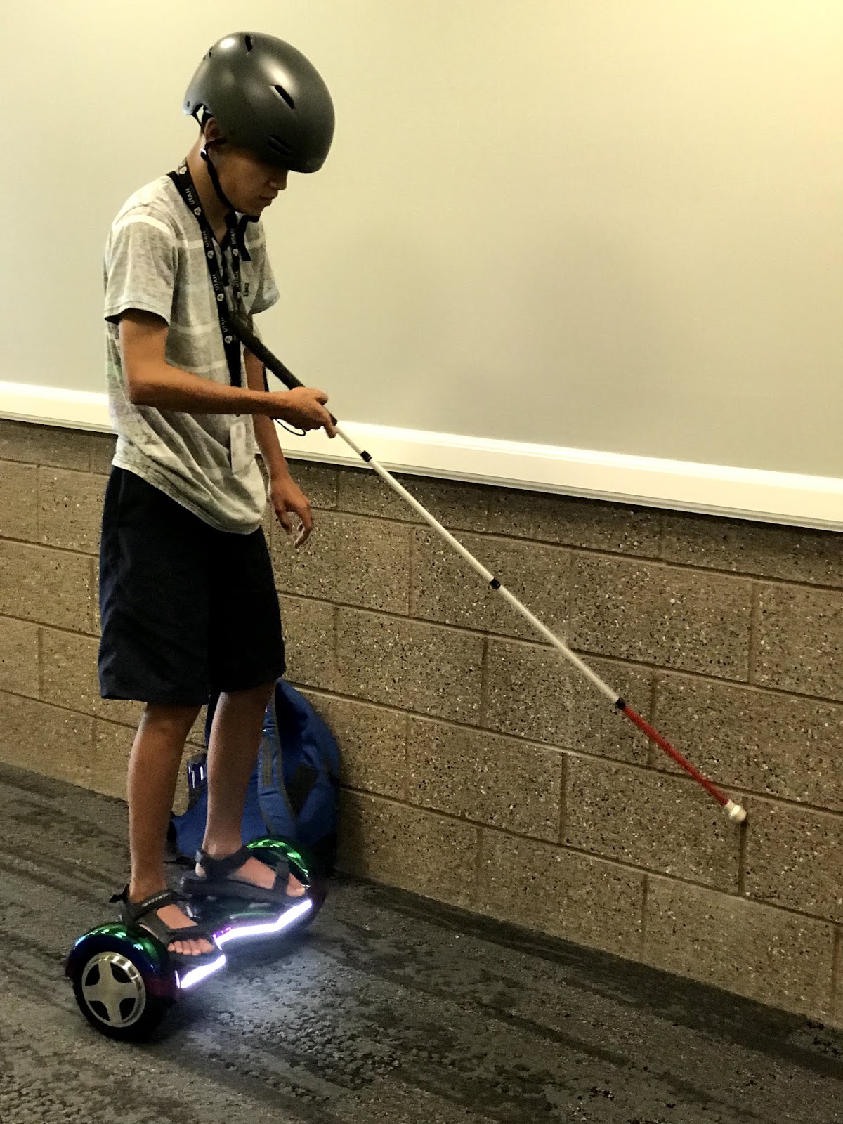 a male teenager moves on the hoverboard and uses his cane