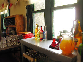 Selection of miniature dolls' house alcoholic and non-alcoholic drinks arranged in a kitchen, ready for a party.
