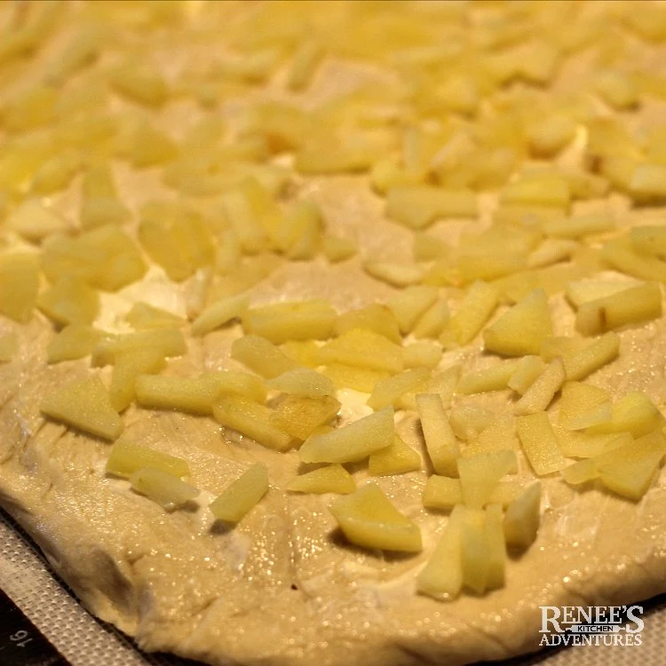 Process image of dough spread with butter and apples for Apple Cinnamon Rolls with Maple Frosting by Renee's Kitchen Adventures