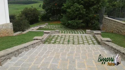 Piso de pedra nos patamares da escada de pedra no jardim com a mureta de pedra com o muro de pedra, as capas do muro com pedra tipo paralelepípedo rachado. Piso de pedra no patamar da escada rejuntado com massa e piso de pedra com junta de grama.