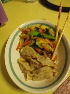 Bowl of potstickers with stir fried vegetables and chopsticks