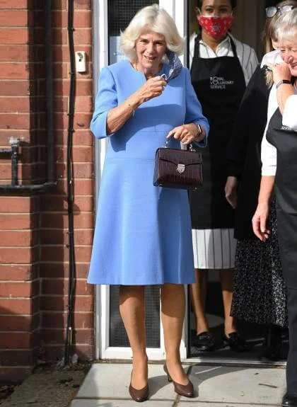 Camilla, Duchess of Cornwall wore a blue wool midi dress, and the mid-length chelsea trench coat from Burberry. British luxury brand Burberry