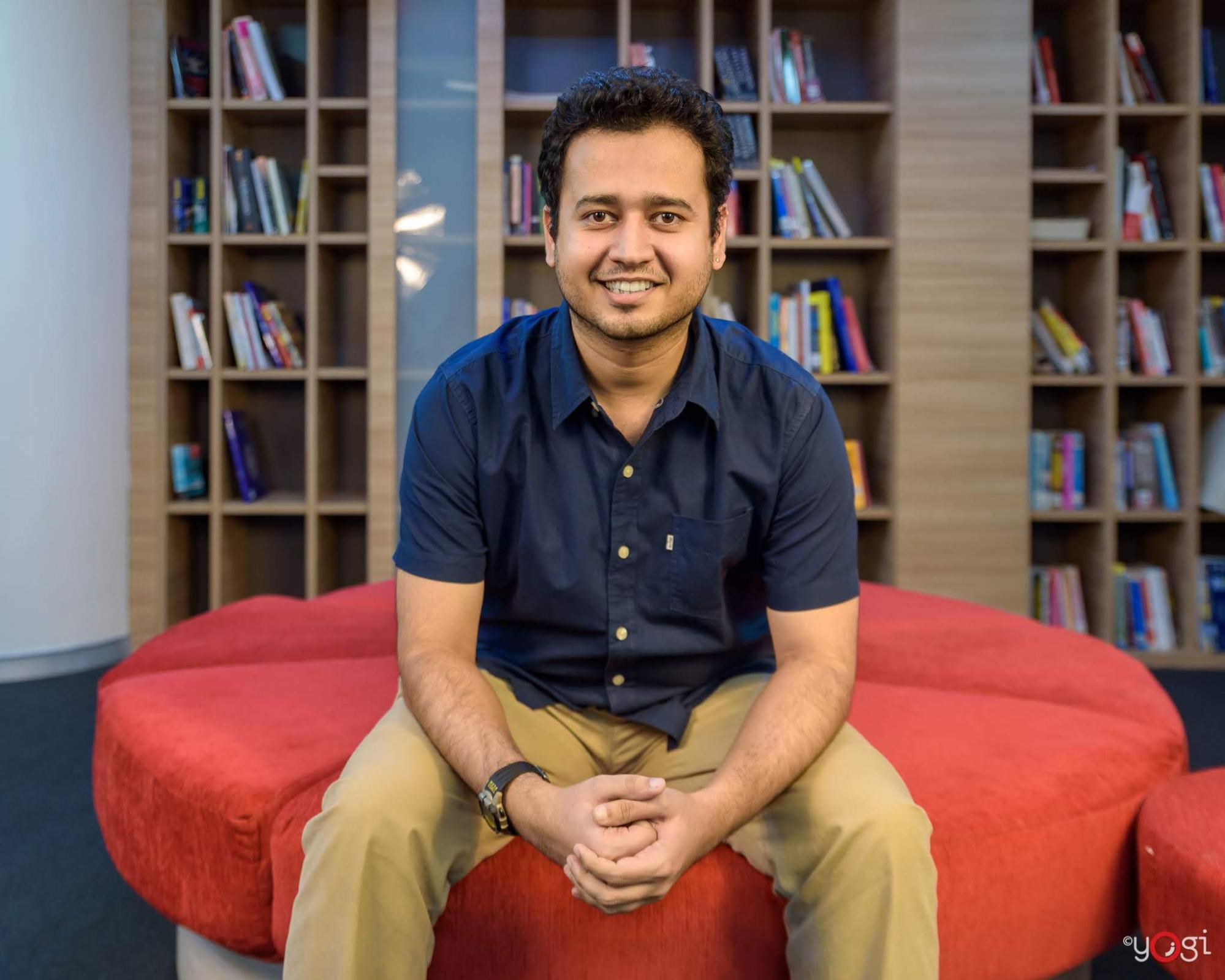 Image shows Bhavesh Bhatt seated and smiling at the camera