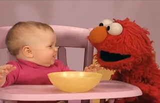 Later Elmo and a baby are on the stage. The baby puts his hand in the bowl. Sesame Street Elmo's World Hands Kids and Baby