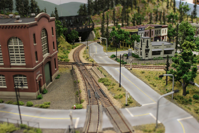 Railroad track and turnout running alongside a plaster road with grade crossings