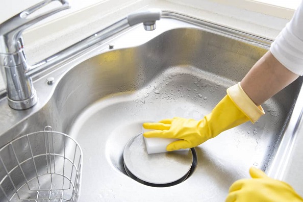 Woman-cleaning-stainless-steel-sink