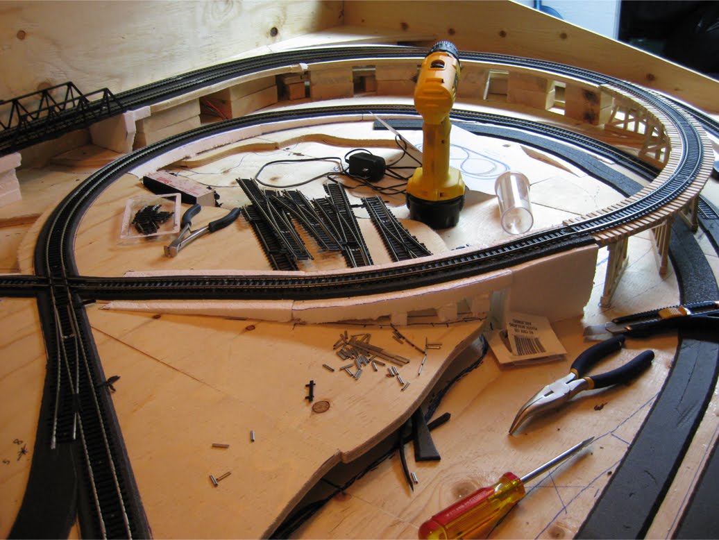 Track being installed on foam roadbed and foam risers leading to a 60 decree rail crossing