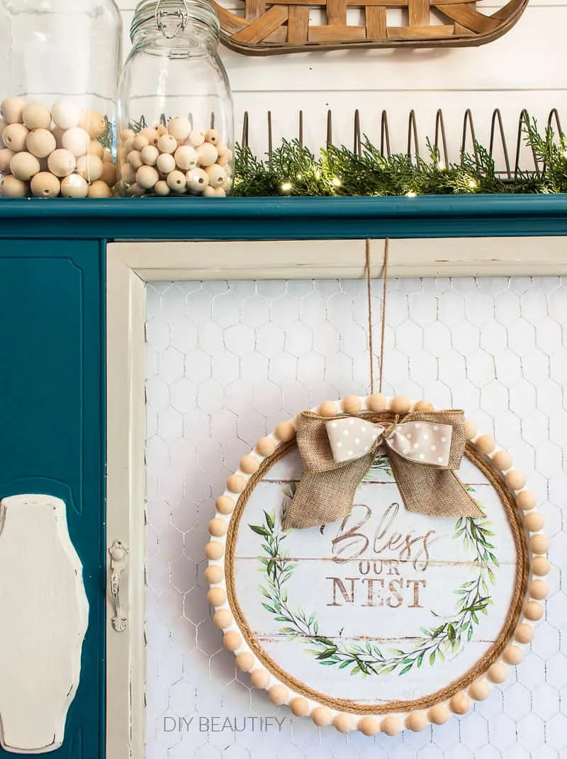 bless our nest farmhouse wreath on blue cabinet