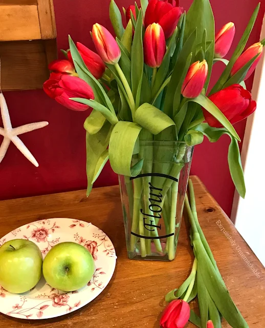 Red Tulips in a glass vase that says flour on it