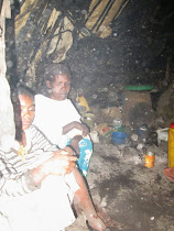 Debre' and watcher inside her fly infested, smoky, leaky plastic hut in the middle of a rain gully