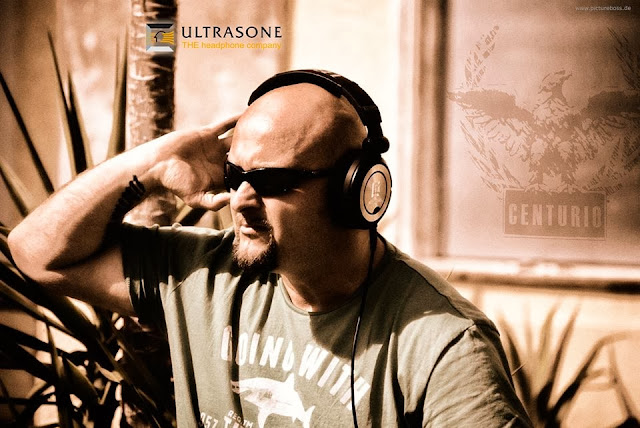 Jens Esch sitting on a sunny day wearing sunglasses and headphones from Ultrasone