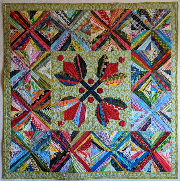 Four crossed tulips center the medallion with string blocks forming Xs as a border