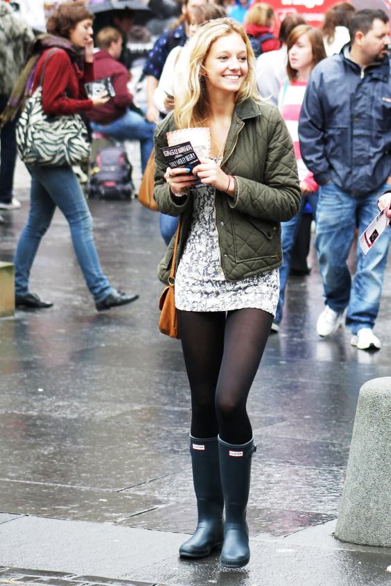 Woman wearing minidress, black tights and black rain boots