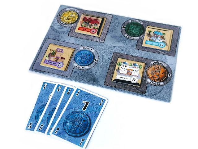 jak grać w alhambrę, zasady i instrukcja Alhambra, na zdjęciu fragment planszy i cztery karty w kolorze niebieskim dające sumę dwanaście czyli tyle ile trzeba aby kupić jeden z kafelków