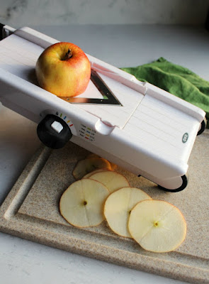 slicing apples thinly on mandolin to make apple chips