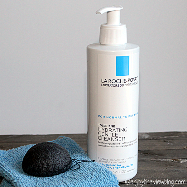 bottle of Toleriane Hydrating Gentle Cleanser, grey konjac sponge, and blue washcloth on a wooden surface