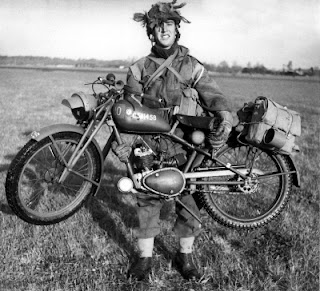 Soldier lifts a small motorcycle to show how light it is.