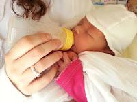 baby being bottle fed by a woman with a ring on her right hand