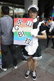 young man holding a sign and dressed up in a maid's outfit at the 2011 Taiwan LGBT Pride Parade