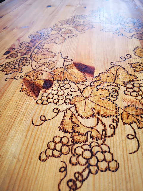odnowiony duży stół z litego drewna z czarnymi nogami i z motywem winogron