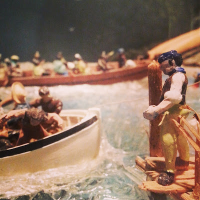 Model of long boats arriving at a wharf.