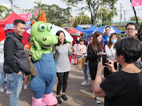 people posing with Ah Tak at the Fa Hui Lunar New Year Fair
