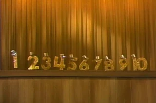 Number One leads the singing numbers. Each of the numbers has a hat on top. Numbers sing One. Sesame Street 123 Count with Me