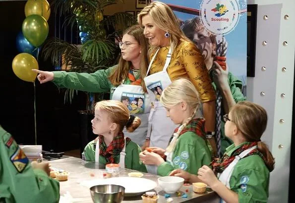 Queen Maxima wore a floral print satin yellow top and floral print blue skirt by Natan. Queen Maxima visited the Scouting Netherlands Cubs