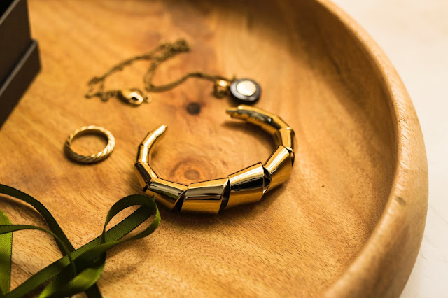 Gold jewelry resting on a wooden dish.