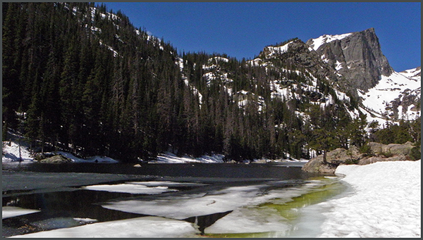 Greenish water and ice in Dream Lake, mountains in background