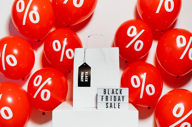 Red balloons, a white shopping bag, and a backlight signage with the text, "BLACK FRIDAY SALE" on the screen.