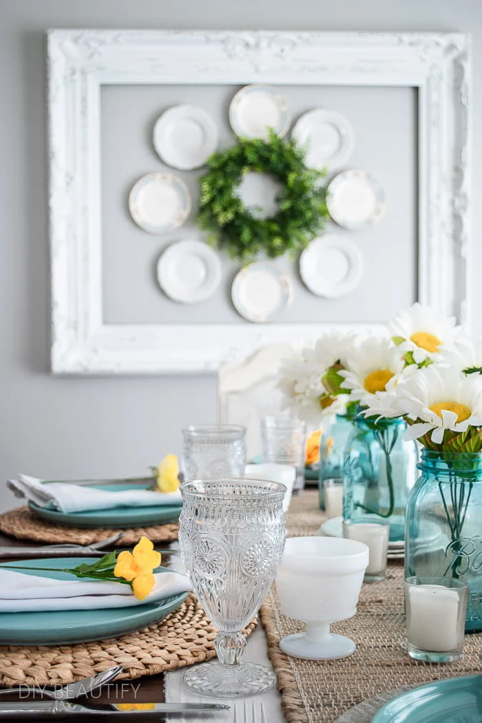 tablescape with beachy blue plates, mason jars, yellow flowers and neutral runner