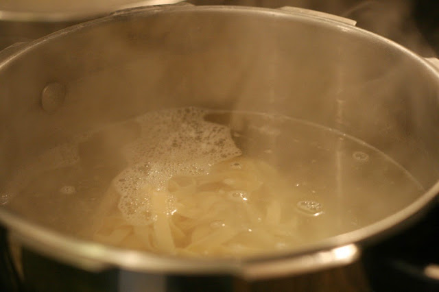 Pot of hot water with pasta inside cooking away. 