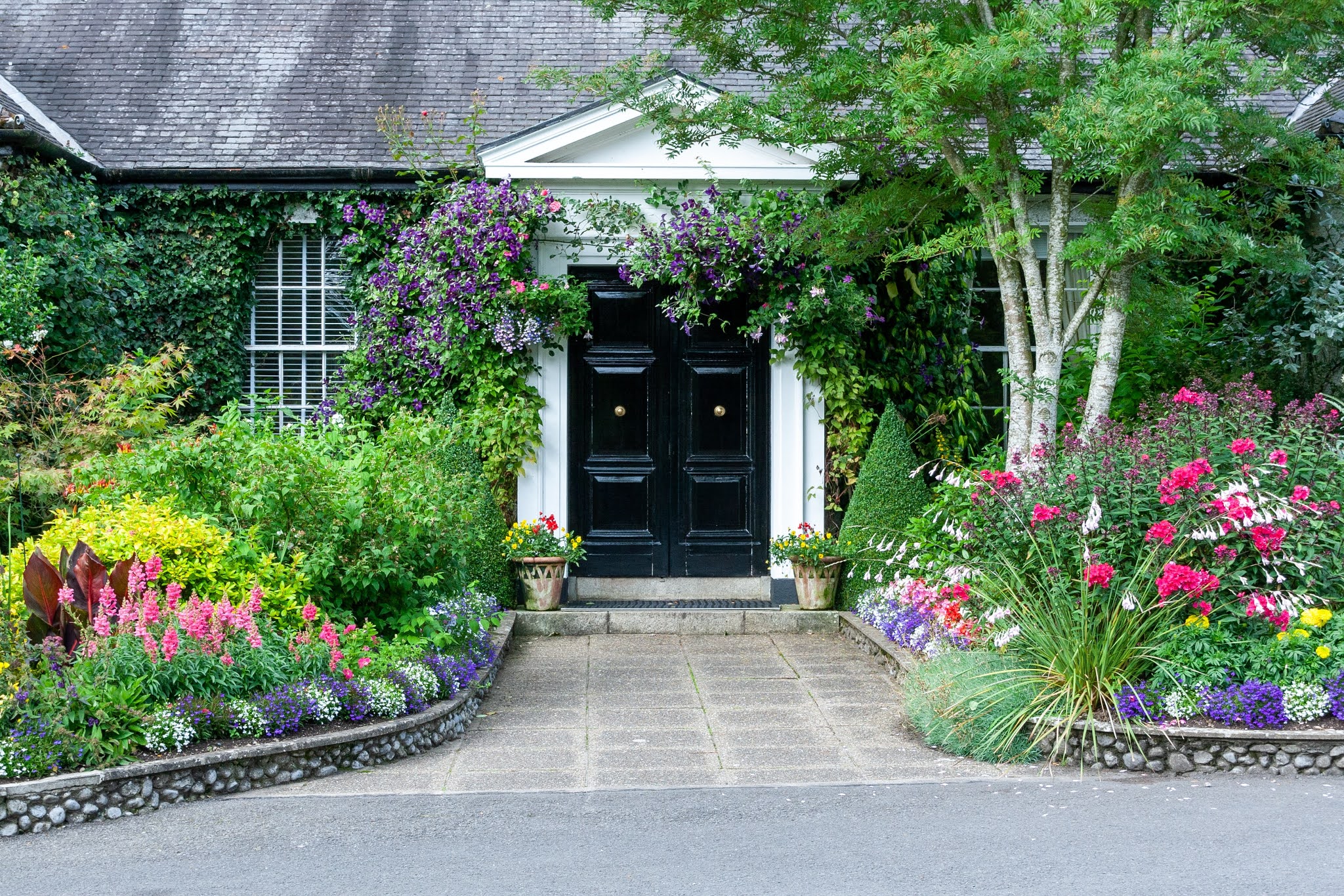 Large doors to a building with flowers and rocks either side