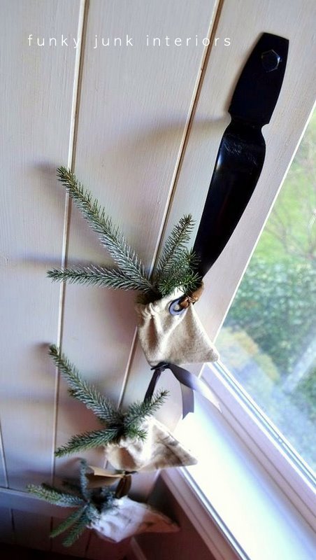 Grain sacks with evergreen branches garland hanging from a door pull as Christmas or winter decorating.