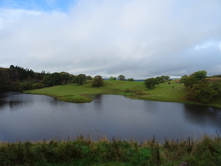 A view of a body of water surrounded by grass and a wooded area.  This being a view from the entrance into Morton Castle.  Photograph by Kevin Nosferatu for the Skulferatu Project.