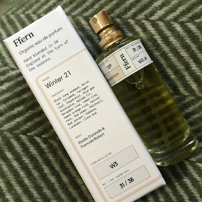 A bottle of perfume lying next to a box saying 'Ffern: Winter 21'