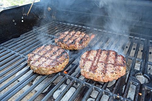Burgers grilling on Char-Broil charcoal to gas combination grill using the charcoal grilling feature