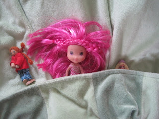 Three small dolls in "bed"