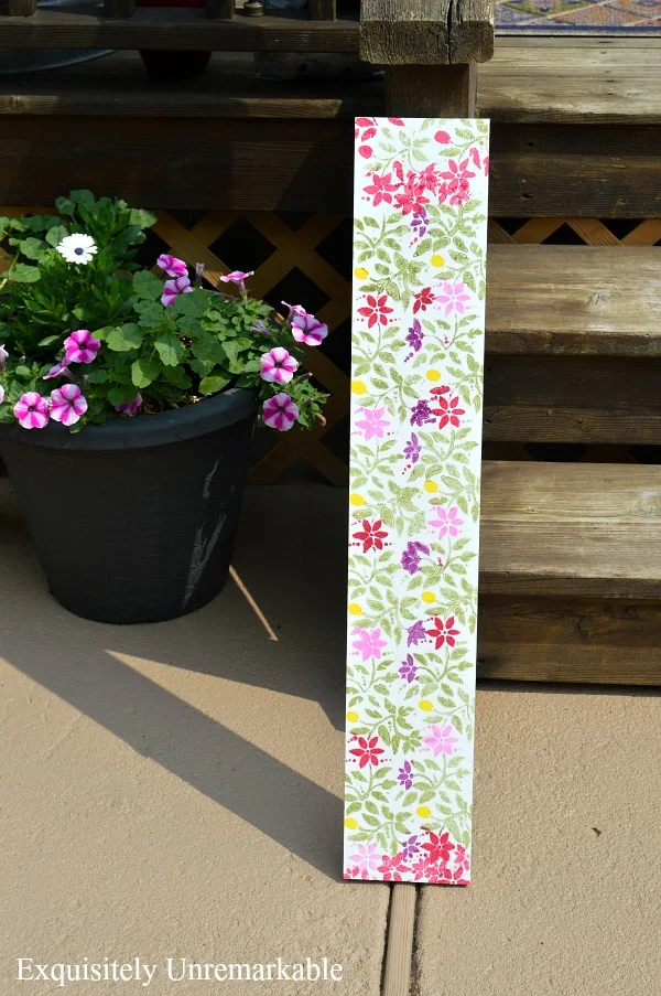 Porch steps with floral wooden board and potted plant