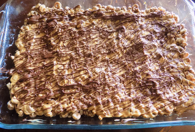 A picture of melted chocolate drizzled over top of peanut butter cereal squares