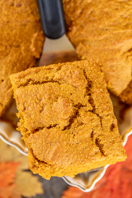 Pumpkin Cornbread - a delicious twist to regular cornbread. Even pumpkin haters LOVE this cornbread. Super easy to make and tastes great. Flour, baking powder, salt, pumpkin pie spice, pumpkin puree, oil, and molasses. Serve with a big dollop of honey butter! Great for Thanksgiving dinner or as a side to your favorite soups and stews. #pumpkin #bread #cornbread slice of pumpkin cornbread