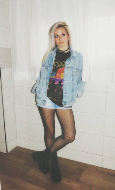 Estilo grunge con camiseta negra ancha con imagen del grupo The Doors, pantalón corto, medias de red pequeña, botas estilo militar y cazadora vaquera