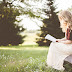 Beautiful Girl Reading a Book Sitting on Stone
