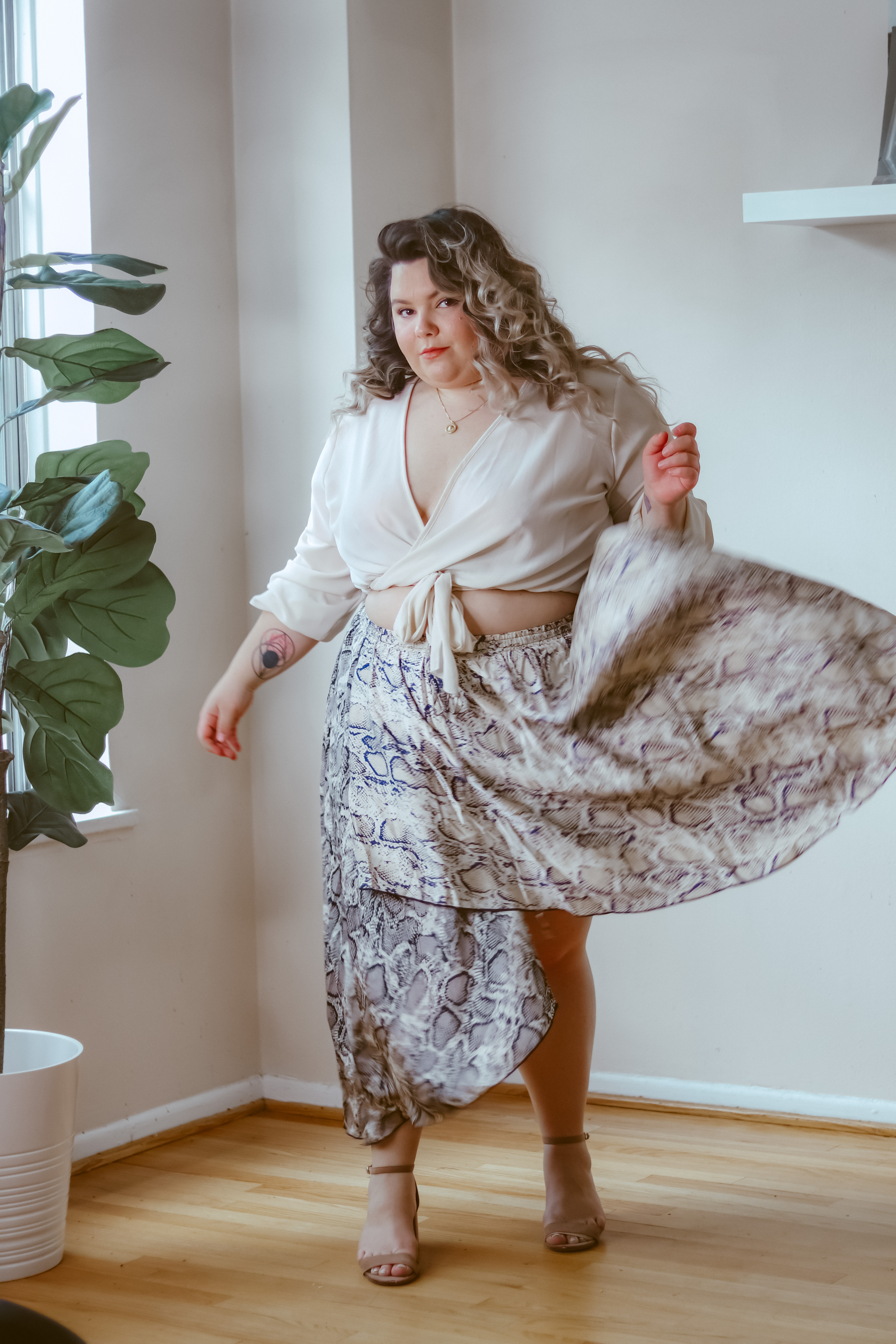 Chicago Plus Size Petite Fashion Blogger, influencer, YouTuber, and model Natalie Craig, of Natalie in the City, styles a snakeskin midi skirt.