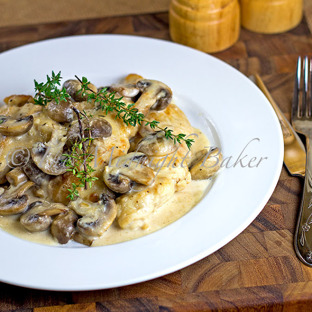 Mushroom Asiago Chicken on a white plate with fresh thyme as garnish